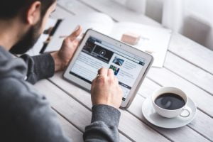 A man in a cafe reading through an article on an Apple iPad