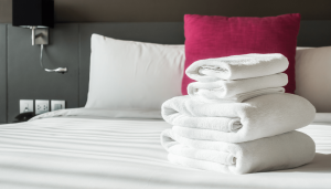bsl_hotel_financeblog_1-min Stack of white towels on a neatly made bed in a hotel