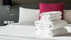 Stack of white towels on a neatly made bed in a hotel