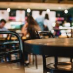 Metal table and chairs in a cafe with people in the background drinking, eating and socializing