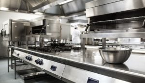 Newly fitted out stainless steel kitchen, a chef is working in the background