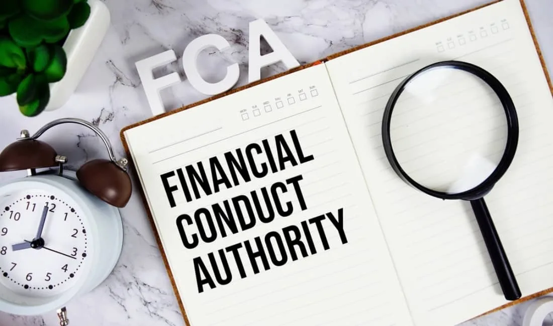 Notebook with "FINANCIAL CONDUCT AUTHORITY" written on the page, with a magnifying glass and clock nearby