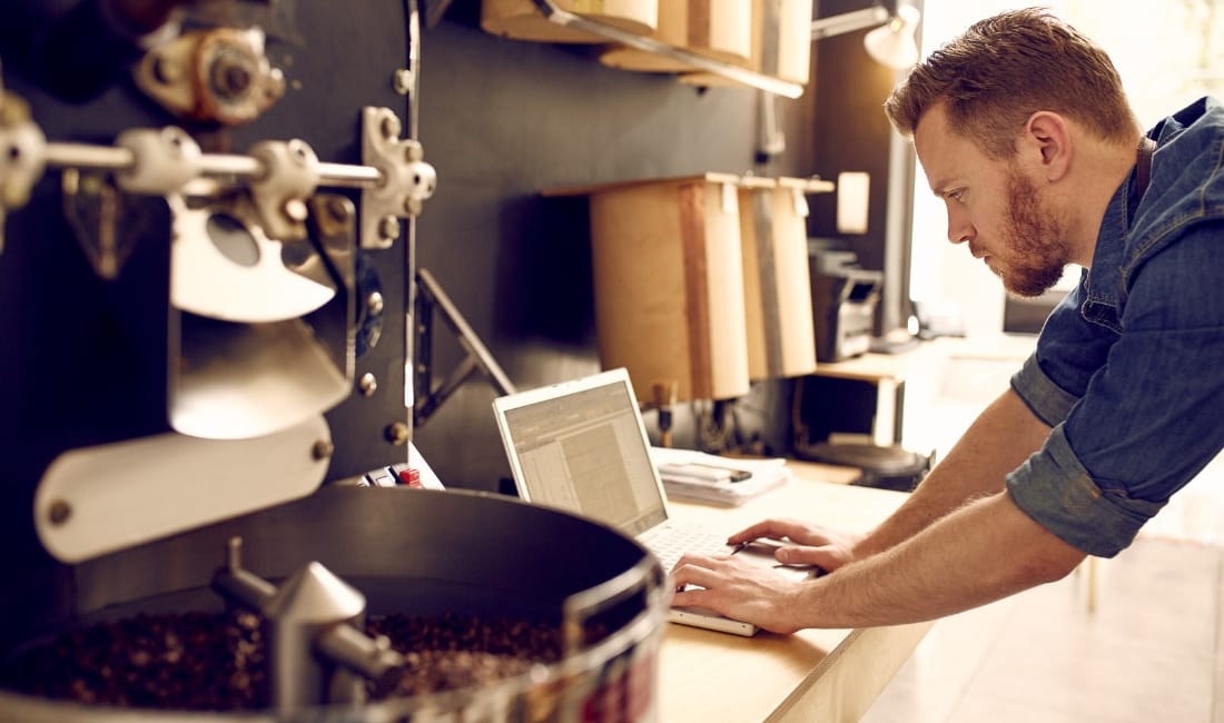 A coffee shop owner access finance for his small business on a laptop