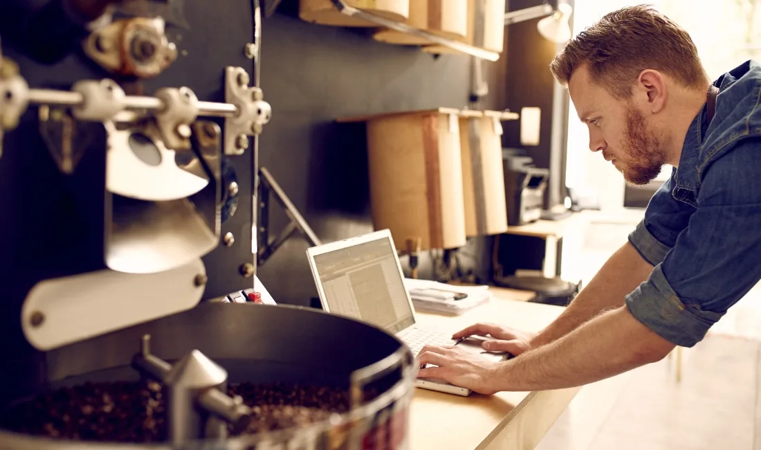A coffee shop owner access finance for his small business on a laptop