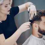Hairdresser cutting mans hair with scissors