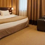 Wide lens view of a newly refurbished hotel room showcasing the bed and large windows