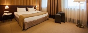 Wide lens view of a newly refurbished hotel room showcasing the bed and large windows