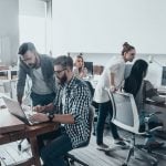 A team of web designers working in their brand new office, featuring wooden floors, computers and bench styled tables