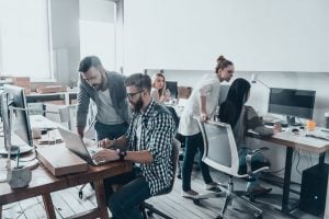 A team of web designers working in their brand new office, featuring wooden floors, computers and bench styled tables