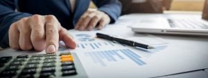 An accountant pointing to business financials which are scattered across his desk