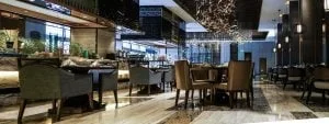A newly fitted out restaurant with a bar featuring fabric chairs, marble floor and elegant decorations hanging from the ceiling