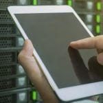 A man configuring settings using an iPad within the server room