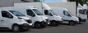 A fleet of white commercial vehicles lined up outside a distribution centre