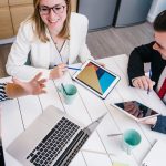 business people in discussion around a table with various form of technology